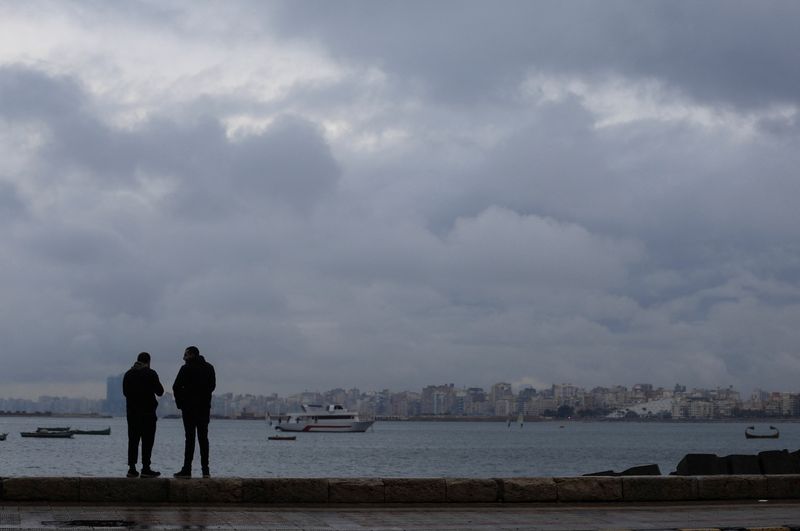 &copy; Reuters. رجلان يقفان أمام البحر في يوم ممطر في مدينة الإسكندرية الساحلية بمصر يوم 31 ديسمبر كانون الأول 2021. تصوير: عمرو عبد الله دلش - رويترز.
