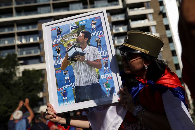 © Reuters. A supporter of Serbian tennis player Novak Djokovic holds his photo during a rally outside the Park Hotel, where the star athlete is believed to be held while he stays in Australia, in Melbourne, Australia, January 9, 2022.  REUTERS/Loren Elliott