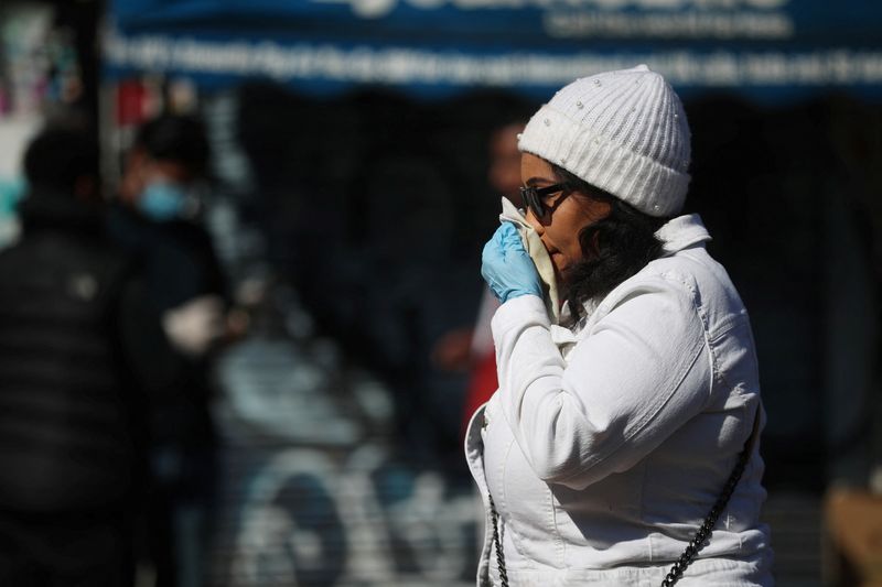 &copy; Reuters. FILE PHOTO: A woman blows her nose in Dalston as the spread of the coronavirus disease (COVID-19) continues, London, Britain, April 14, 2020. REUTERS/Hannah McKay