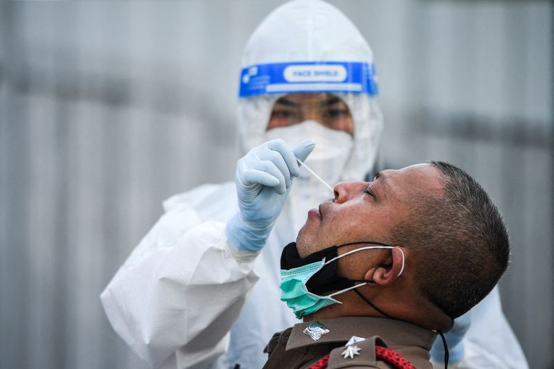 &copy; Reuters. FILE PHOTO: A health worker in personal protective equipment (PPE) takes a swab sample from a police officer for a rapid antigen test amid the coronavirus disease (COVID-19) outbreak, in Bangkok, Thailand, January 7, 2022. REUTERS/Chalinee Thirasupa