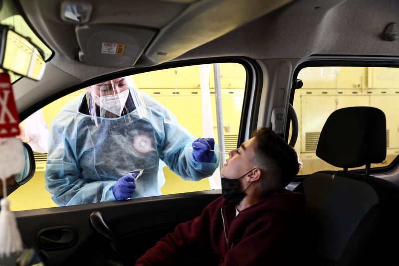 © Reuters. صبي أثناء فحصه للكشف عن فيروس كورونا في سيارته في القدس يوم الاثنين مع تزايد اعداد المصابين بسلالة أوميكرون في اسرائيل. تصوير:رويترز.