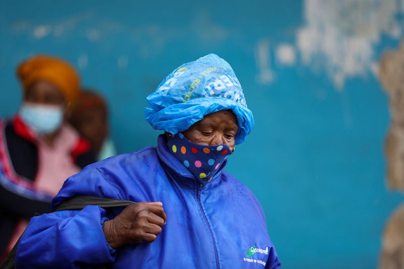 &copy; Reuters. A woman wearing a protective face mask against the coronavirus disease (COVID-19) and a plastic bag on her head to protect from the rain looks on, as the new Omicron coronavirus variant spreads, at Tsomo, a town in the Eastern Cape province of South Afric