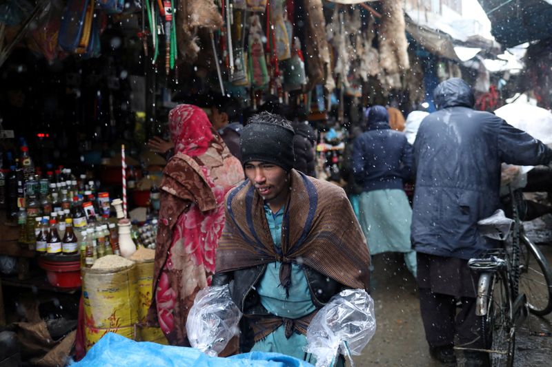 &copy; Reuters. Afghan men walk in a market area during a snowfall in Kabul, Afghanistan, January 3, 2022. REUTERS/Ali Khara