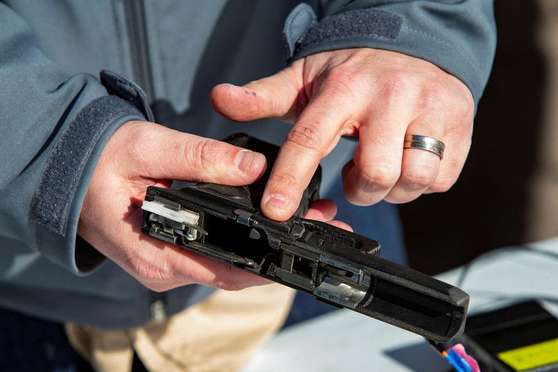 © Reuters. Rob Regent of SGW Designworks breaks down the inner working of the 9mm smart gun, which works only for the designated user, during a presentation for shareholders and potential investors in Boise, Idaho, U.S. January 7, 2022.  REUTERS/Brian Losness