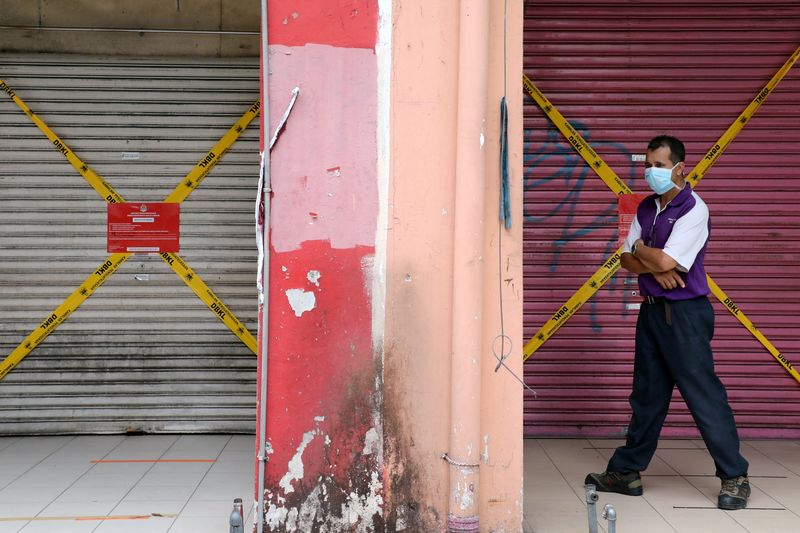 &copy; Reuters. Homem usando máscara protetora passa por lojas fechadas, em meio ao surto de Covid-19 em Kuala Lumpur, Malásia, 28 de maio de 2020. REUTERS/Lim Huey Teng