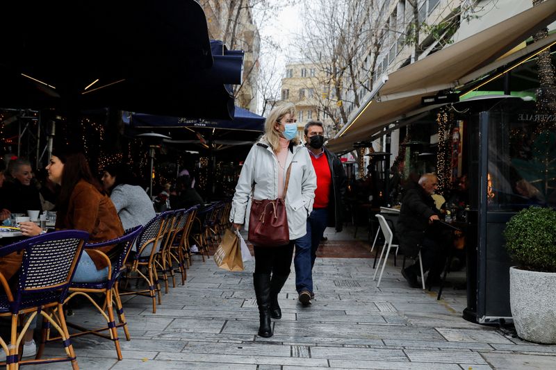 &copy; Reuters. FILE PHOTO: People wearing protective face masks walk past a cafe amid the coronavirus disease (COVID-19) outbreak in Athens, Greece, December 28, 2021. REUTERS/Costas Baltas