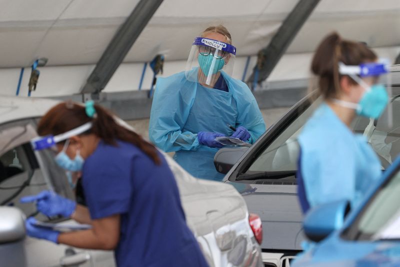 &copy; Reuters. FILE PHOTO: Medical workers administer tests at the Bondi Beach drive-through coronavirus disease (COVID-19) testing centre in the wake of an outbreak in Sydney, Australia, December 22, 2020. REUTERS/Loren Elliott
