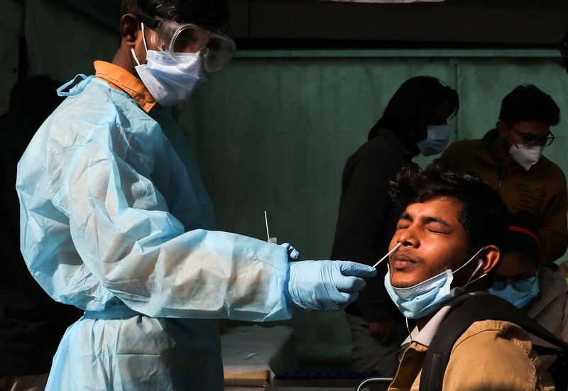 &copy; Reuters. FILE PHOTO: A healthcare worker collects a coronavirus disease (COVID-19) test swab sample from a man, amidst the spread of the disease, at a railway station in New Delhi, India, January 11, 2022. REUTERS/Anushree Fadnavis