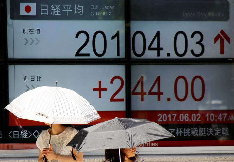 &copy; Reuters. Women holding parasols walk past an electronic board showing Japan's Nikkei average rate outside a brokerage in Tokyo, Japan June 2, 2017. REUTERS/Toru Hanai