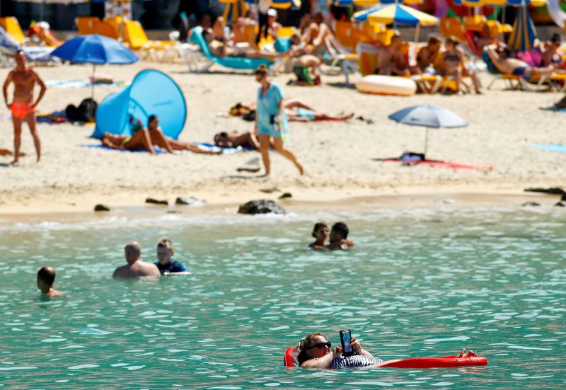 &copy; Reuters. FILE PHOTO: A tourist sunbathes on an air mattress with her phone on the Amadores beach in the south of the island of Gran Canaria, Spain, August 3, 2021. REUTERS/Borja Suarez/File Photo