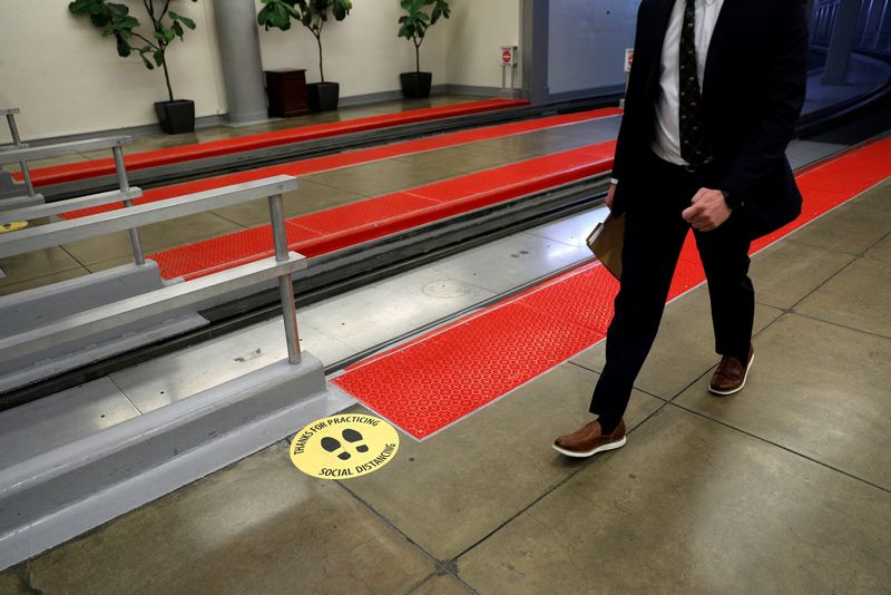 &copy; Reuters. A reporter walks past a protective social distancing sticker at the Senate Subway rail platform on Capitol Hill in Washington, U.S., December 3, 2020. REUTERS/Tom Brenner