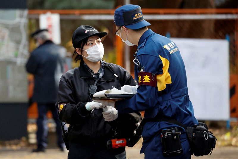 &copy; Reuters. A police investigator speaks to another person at the site where a stabbing incident happened at an entrance gate of Tokyo University in Tokyo, Japan January 15, 2022. REUTERS/Issei Kato