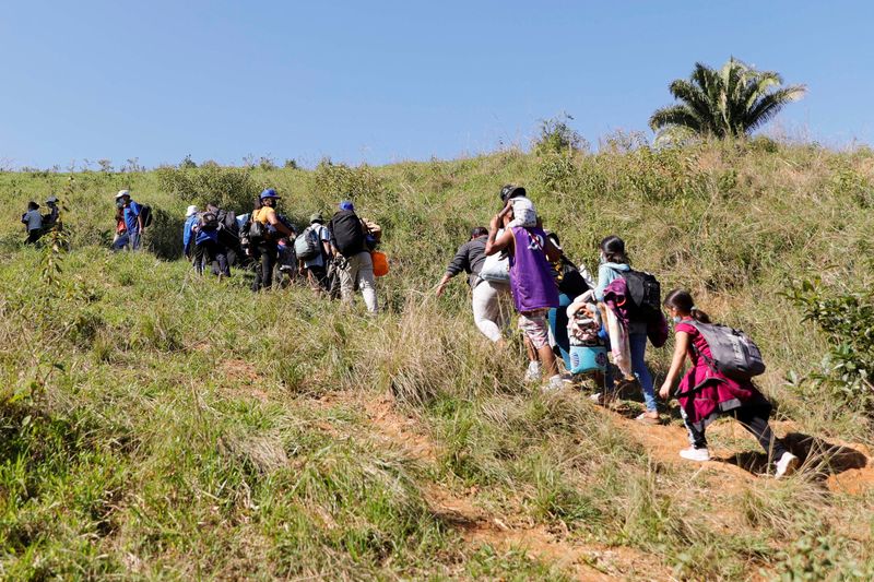 &copy; Reuters. مهاجرون من أمريكا الوسطى يصعود تلا لتجنب سلطات الهجرة حيث يسيرون في قافلة باتجاه الولايات المتحدة بالقرب من حدود جواتيمالا في كورينتو بهند