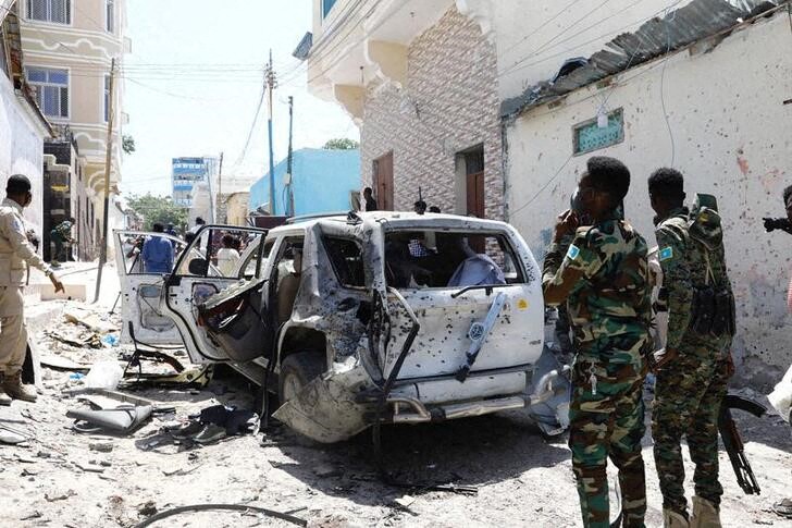 © Reuters. فردان من قوات أمن الصومال يتفحصان حطام سيارة في موقع انفجار مقديشو يوم الأحد. تصوير: فيصل عمر - رويترز.