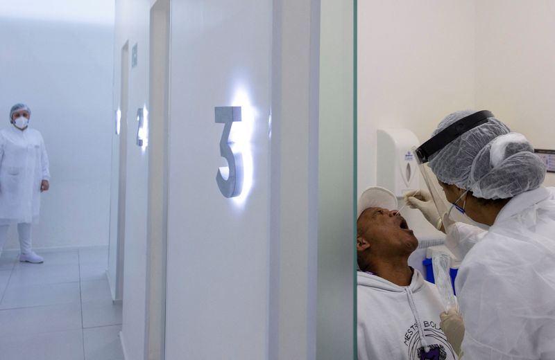 &copy; Reuters. أحد العاملين في قطاع الرعاية الصحية تأخذ مسحة من رجل لاختبار الإصابة بفيروس كورونا في معمل بمطار ساو باولو في جوارولوس يوم 12 يناير كانون الث