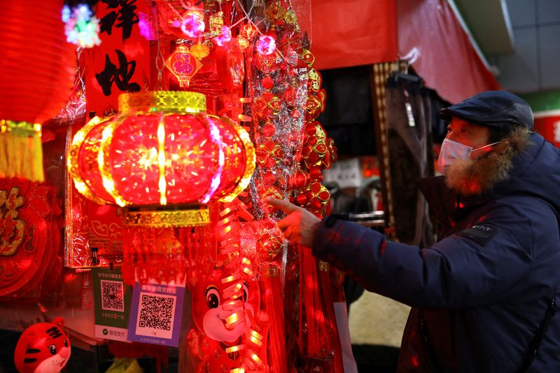 © Reuters. A customer looks at decorations for Chinese Lunar New Year displayed at a stall inside a morning market in Beijing, China January 14, 2022. Picture taken January 14, 2022. REUTERS/Tingshu Wang