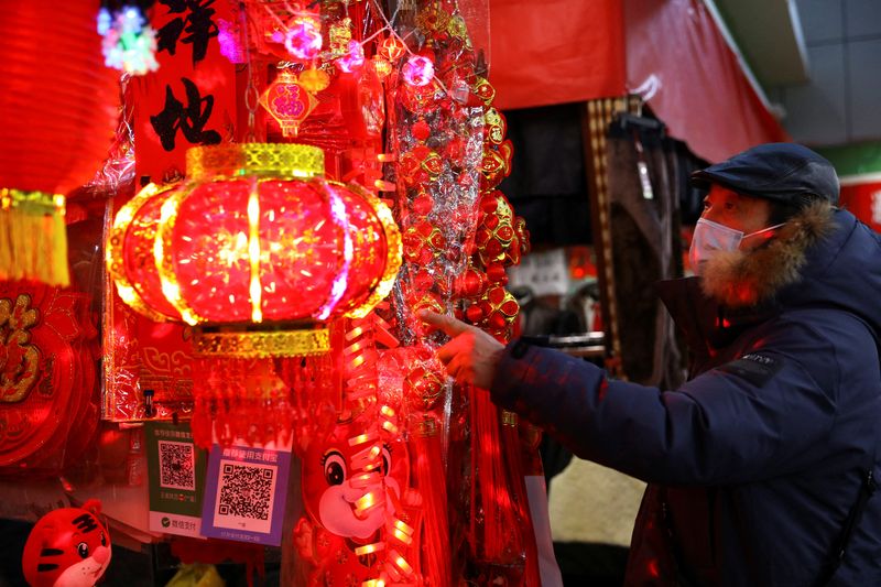 &copy; Reuters. Un hombre con mascarilla observa varios objetos de decoración en un mercado de Pekín