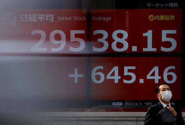 &copy; Reuters. A man wearing a protective face mask stands in front of an electronic board showing Japan’s Nikkei share average, amid the coronavirus disease (COVID-19) pandemic, in Tokyo, Japan November 1, 2021. Picture taken with a slow shutter speed.  REUTERS/Issei