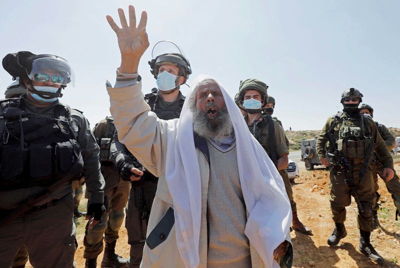 &copy; Reuters. الشيخ الفلسطيني سليمان الهذالين أمام جنود إسرائيليين خلال احتجاج على المستوطنات في يطا بالضفة الغربية المحتلة يوم 19 مارس آذار 2021. تصوير: مو