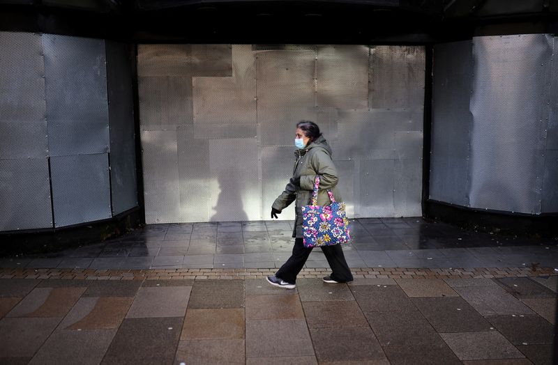 &copy; Reuters. FILE PHOTO: A woman wearing a face mask walks past a closed shop, amid the coronavirus disease (COVID-19) outbreak, in Preston, Britain, January 11, 2022. REUTERS/Phil Noble