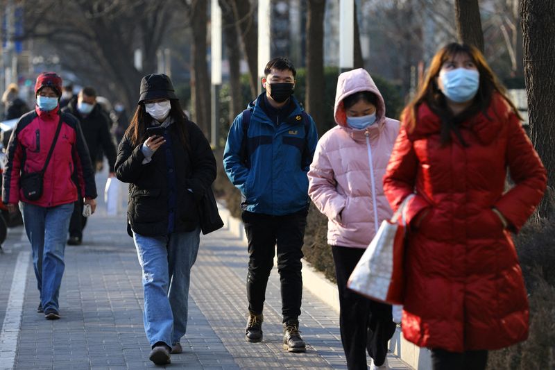 &copy; Reuters. FILE PHOTO: People wearing protective face masks walk on a street during morning rush hour, as the coronavirus disease (COVID-19) pandemic continues in the country, in Beijing, China January 18, 2022. REUTERS/Tingshu Wang