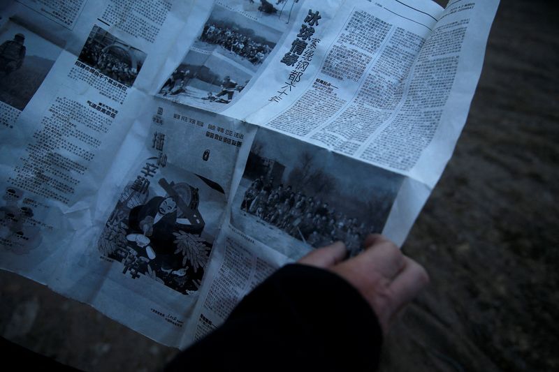 &copy; Reuters. Li Bingru holds a newspaper showing a photo of himself in the local ice hockey team in 1986, in Anshan, Liaoning province, China, December 25, 2021. REUTERS/Tingshu Wang