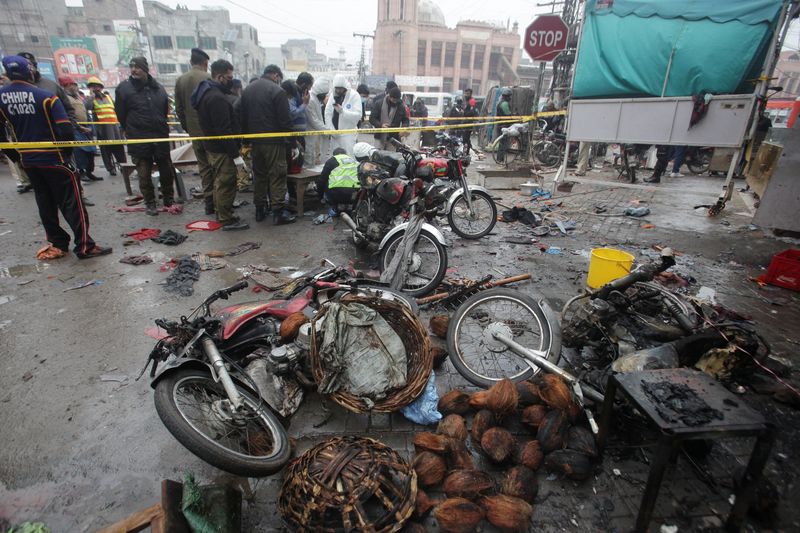 &copy; Reuters. أعضاء من وحدة مسرح الجريمة وفريق التخلص من القنابل يتجمعون بعد انفجار في سوق في لاهور في باكستان يوم الخميس. تصوير: محسن رضا - رويترز.