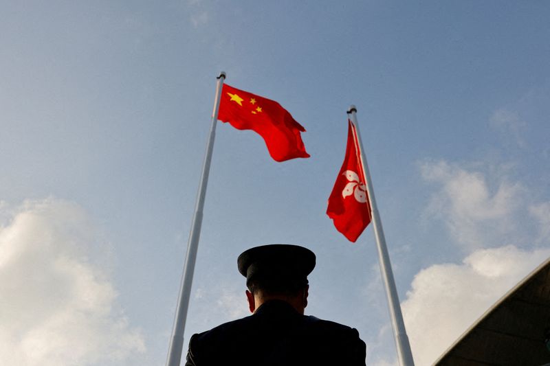 &copy; Reuters. FILE PHOTO: A police officer stands guard below China and Hong Kong flags during a flag raising ceremony, a week ahead of the Legislative Council election in Hong Kong, China, December 12, 2021. REUTERS/Tyrone Siu/File Photo