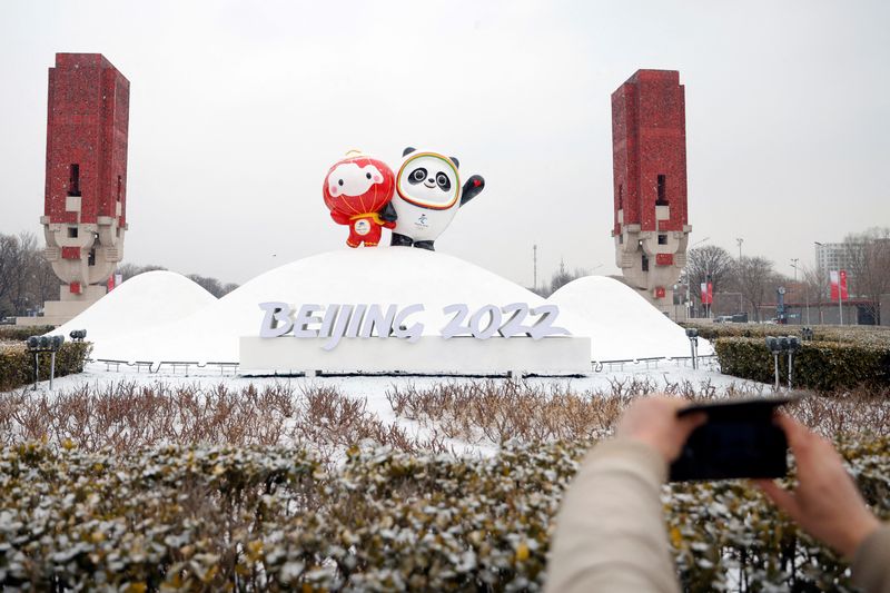 &copy; Reuters. Un peatón toma fotos de una instalación con Bing Dwen Dwen y Shuey Rhon Rhon, mascotas de los Juegos Olímpicos y Paralímpicos de Invierno de Pekín 2022, en medio de una nevada en Pekín, China. 20 de enero de 2022. REUTERS/Carlos García Rawlins