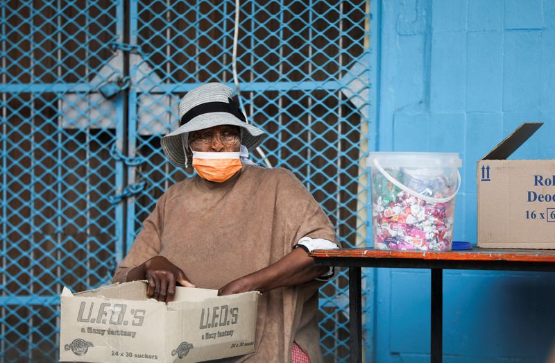 &copy; Reuters. FILE PHOTO: A woman wearing a protective face mask against the coronavirus disease (COVID-19) sits next to her stall, as the new Omicron coronavirus variant spreads, at Tsomo, a town in the Eastern Cape province of South Africa, December 2, 2021.  REUTERS