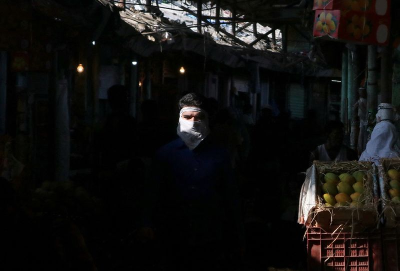 &copy; Reuters. رجل يضع كمامة للوقاية من فيروس كورونا يسير داخل سوق في مومباي بالهند - صورة من أرشيف رويترز 