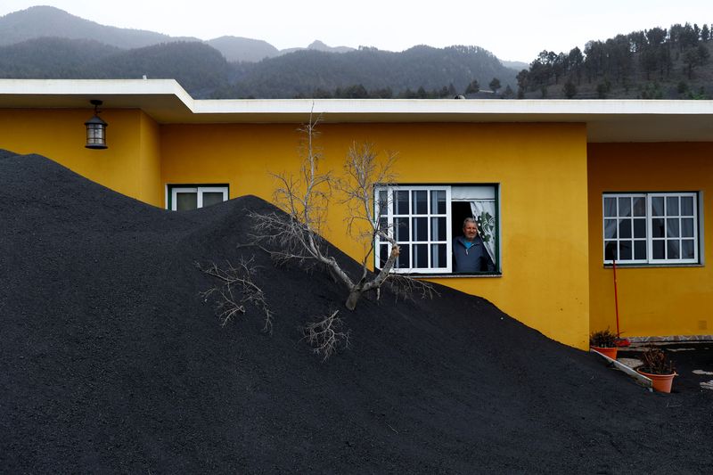&copy; Reuters. Dionisio Leal observa desde una ventana las pilas de ceniza volcánica que rodean su casa en el barrio de Las Manchas, en la isla de La Palma, Islas Canarias, España, el 20 de enero de 2022. REUTERS/Borja Suárez