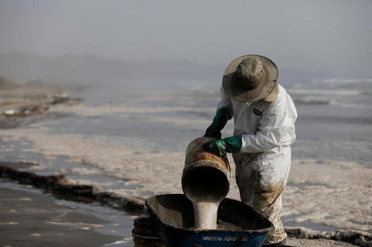 &copy; Reuters. IMAGEN DE ARCHIVO. Un trabajador limpia un derrame de petróleo, en medio del descarge de un tanquero, causado por olas anormales provocadas por una erupción volcánica submarina en Tonga, frente a la costa de Lima, en Ventanilla, Perú, 19 de enero de 2
