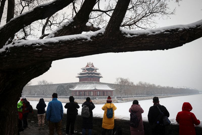 &copy; Reuters. People take pictures of the Forbidden City after an overnight snowfall as the spread of the coronavirus disease (COVID-19) continues, in Beijing, China, January 22, 2022. REUTERS/Thomas Peter