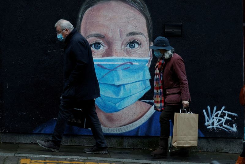 &copy; Reuters. FILE PHOTO: People wearing face masks walk past a mural of a nurse in the centre of Manchester, Britain, November 29, 2021. REUTERS/Phil Noble