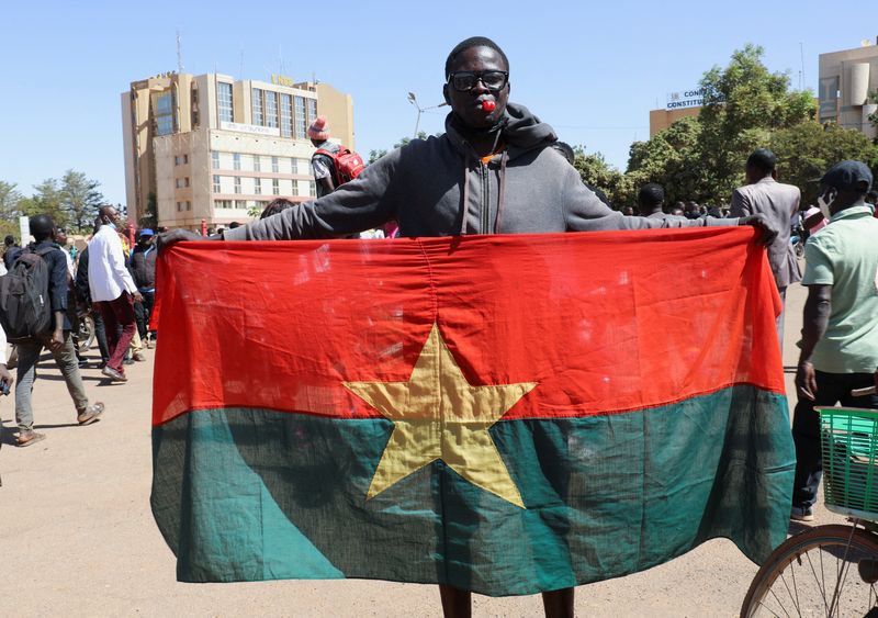 © Reuters. رجل يحمل علم بوركينا فاسو لإظهار الدعم للجيش في البلاد بعد أنباء عن احتجاز الرئيس كابوري في ثكنة عسكرية في واجادوجو يوم الاثنين. تصوير فينسنت بادو- رويترز.