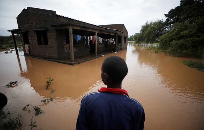 © Reuters. طفل ينظر إلى منزله الذي حاصرته مياه الفيضان الناجم عن إعصار في قرية بموزامبيق في 2019. صورة من أرشيف رويترز.  