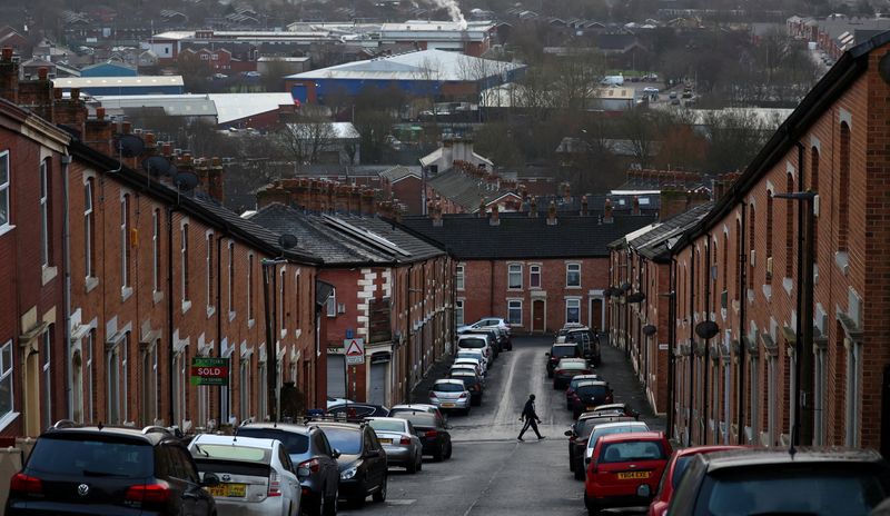 &copy; Reuters. FILE PHOTO: A person walks across a street lined with terraced housing in Blackburn, Britain, January 17, 2022. REUTERS/Phil Noble