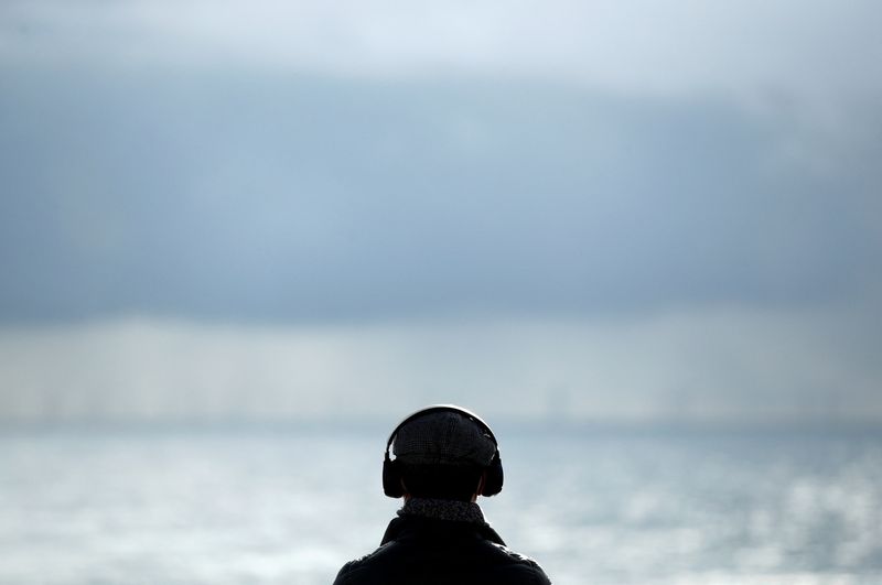 &copy; Reuters. FILE PHOTO: A man wearing headphones looks at the view, as the spread of the coronavirus disease (COVID-19) continues, in Brighton, Britain, November 10, 2020. REUTERS/Peter Cziborra