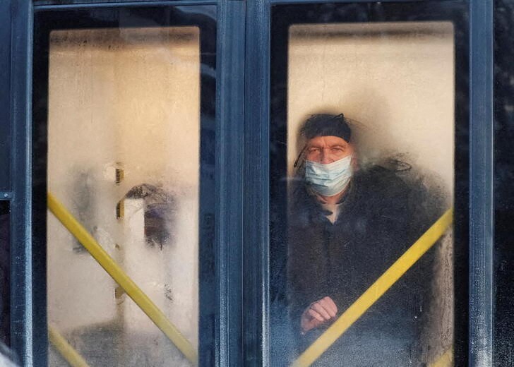 &copy; Reuters. A passenger wearing a protective face mask is seen through a frost-covered bus window, amid the ongoing coronavirus disease (COVID-19) outbreak, on a freezing day in Kyiv, Ukraine December 22, 2021. REUTERS/Gleb Garanich