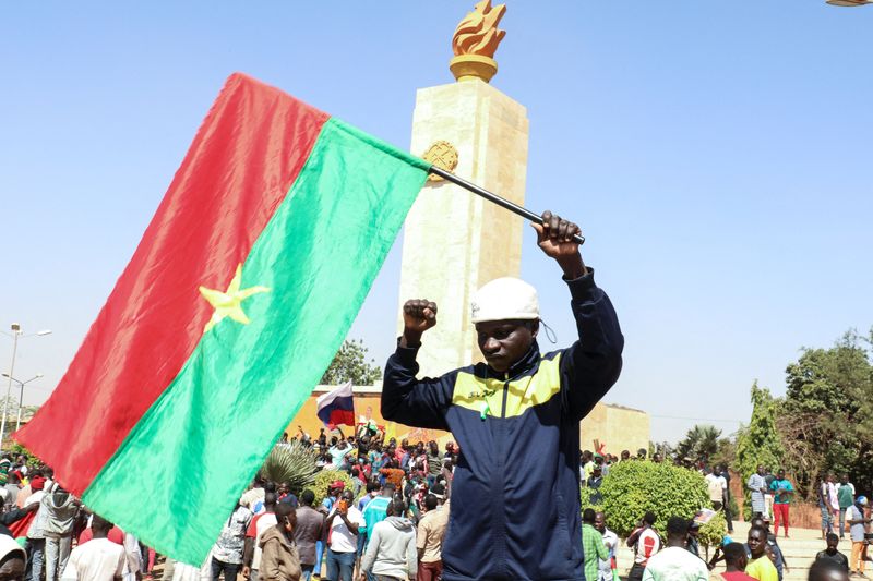 &copy; Reuters. Un hombre sostiene una bandera nacional mientras la gente se reúne en apoyo del golpe de Estado que derrocó al presidente Roch Kabore, disolvió el Gobierno, suspendió la constitución y cerró las fronteras en Burkina Faso, en Uagadugú, 25 de enero d