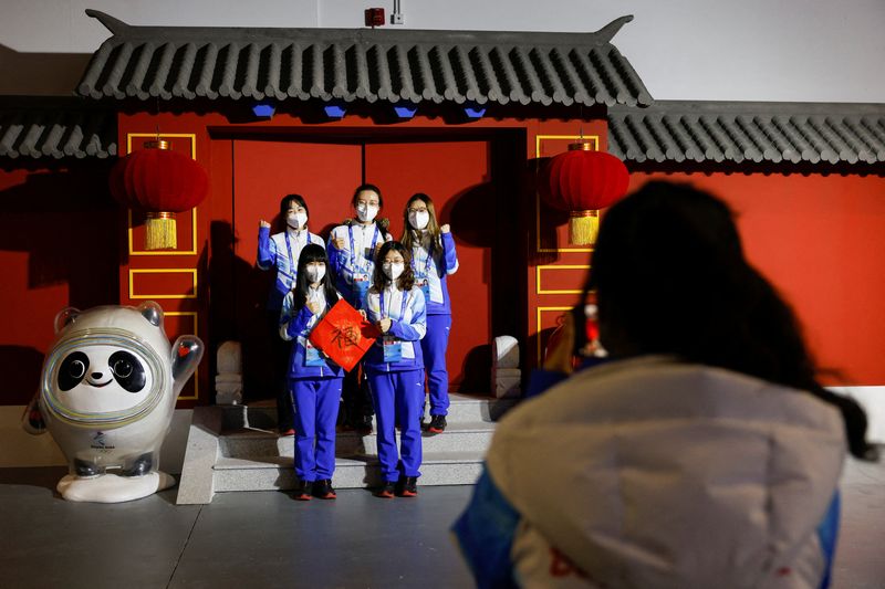 &copy; Reuters. Volunteers pose for photo next to the installation of Bing Dwen Dwen and Shuey Rhon Rhon, mascots of the Beijing 2022 Winter Olympics and Paralympics, at the Main Press Centre ahead of the Beijing 2022 Winter Olympics, in Beijing, China January 26, 2022. 