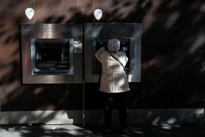 &copy; Reuters. FILE PHOTO: A woman uses a Caixabank branch ATM machine displaying logos of both Caixabank and Bankia banks in Madrid, Spain, November 10, 2021. REUTERS/Susana Vera