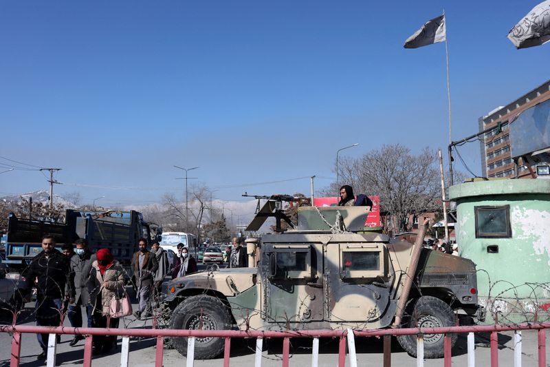&copy; Reuters. Afghans walk past a Humvee with a Taliban fighter on it guarding the road in Kabul, Afghanistan, January 27, 2022. REUTERS/Ali Khara