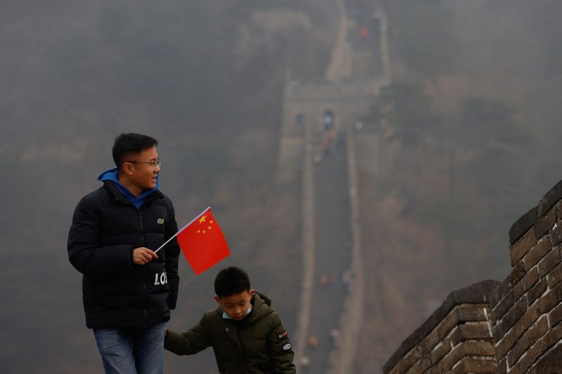 &copy; Reuters. Imagen de archivo de un hombre sosteniendo una bandera china mientras camina por la sección Mutianyu de la Gran Muralla de China durante un día con aire contaminado, luego de un brote de COVID-19, en Pekín, China. 13 de febrero, 2021. REUTERS/Carlos Ga