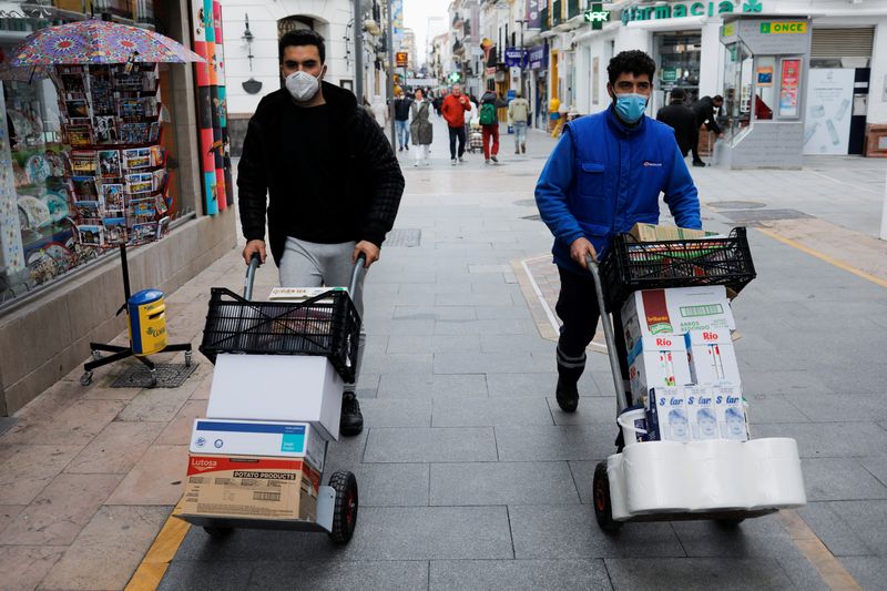 © Reuters. Delivery men push carts in downtown Ronda, Spain, January 27, 2022. REUTERS/Jon Nazca