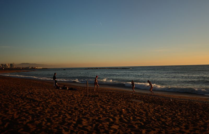 © Reuters. Tourists are pictured in the winter sun after swimming during a sunrise at Barceloneta beach, amid the outbreak of the coronavirus disease (COVID-19), as the Spanish government considers the sixth wave of COVID-19 to be coming to an end, in Barcelona, Spain February 1, 2022. Picture taken February 1, 2022. REUTERS/Nacho Doce