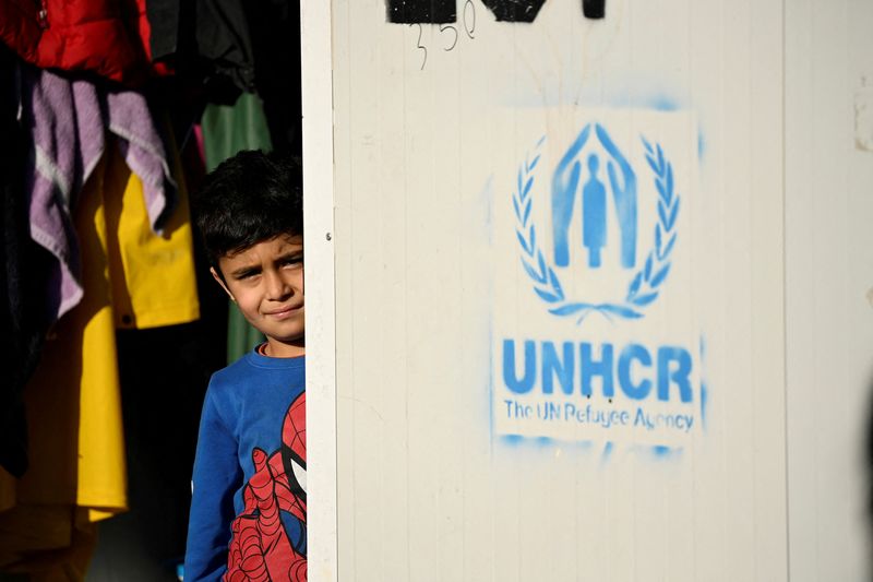 &copy; Reuters. FOTO DE ARCHIVO: Un niño junto al logotipo de la ACNUR (UNHCR, por sus siglas en inglés) en el campo de refugiados de Mavrovouni en la isla de Lesbos, Grecia, el 5 de diciembre de 2021.  Vatican Media/­Cedida a través de REUTERS  