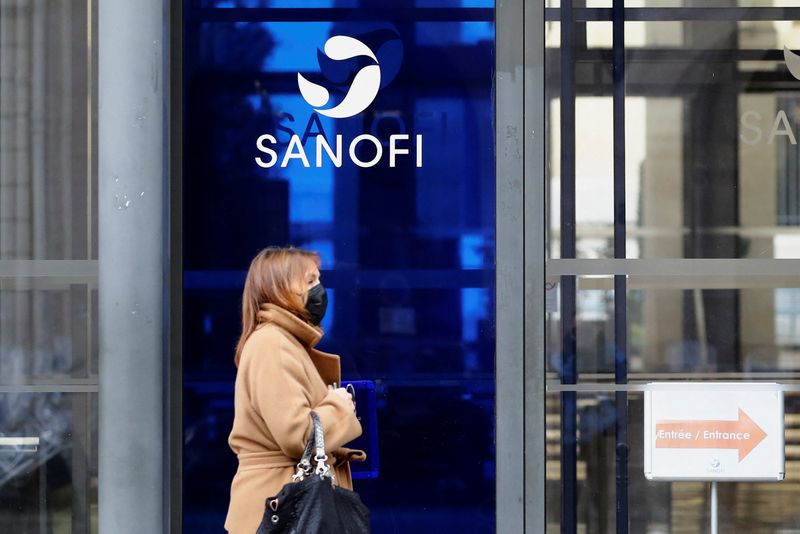 © Reuters. FILE PHOTO: A woman, wearing a protective face mask, walks past the logo of Sanofi at the company's headquarters in Paris, France, January 31, 2022. REUTERS/Violeta Santos Moura