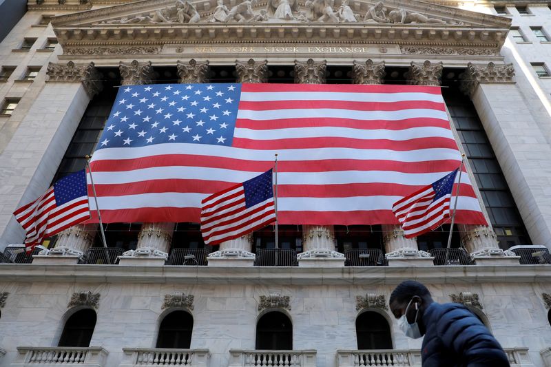 © Reuters. FILE PHOTO: A man in a surgical mask walks by the New York Stock Exchange (NYSE) as coronavirus continued to influence markets in Manhattan, New York City, New York, U.S., March 16, 2020. REUTERS/Andrew Kelly/File Photo